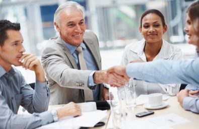 Senior business man congratulating a colleague during a meeting